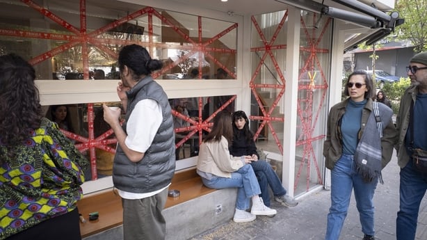 Iranian youths gather outside a cafe as tape covers the windows to protect them from shattering caused by an explosion's shockwave, in Tehran, Iran, on April 5, 2026, amid the U.S.-Israeli military operation in Iran. As the military operation enters its thirty-seventh day, Iranians express concern o