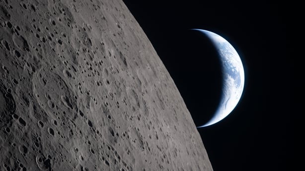 The earth is seen in the distance behind the moon