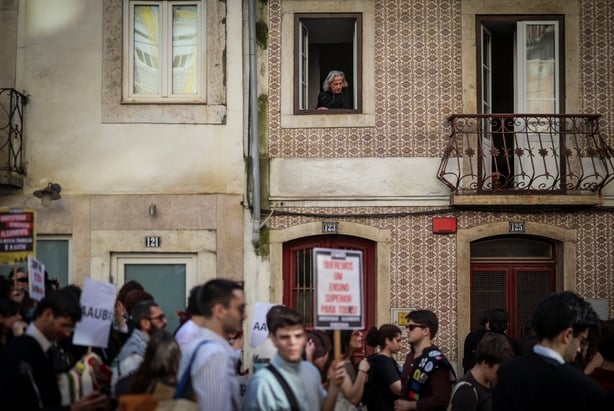A man watches from his window as students demonstrate to ask affordable housing, an end to tuition fees, and investment in social programs in Lisbon on March 24, 2026.