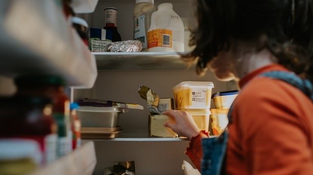 A child opens a refrigerator and reaches inside.