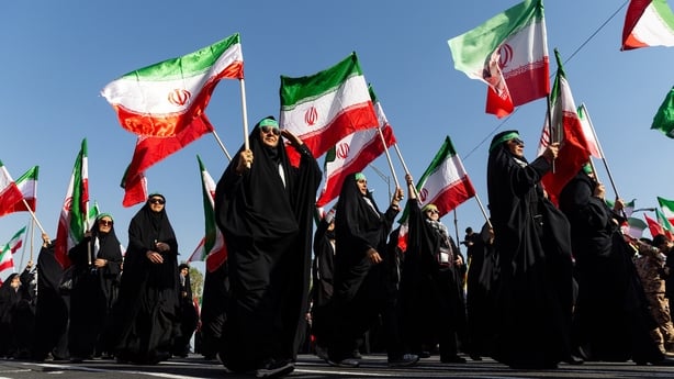 women salute and carry iranian flags