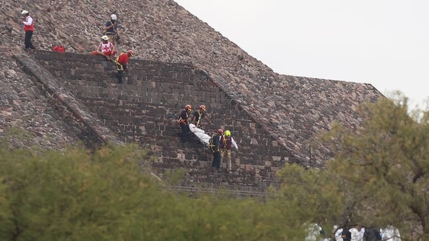 Red Cross personnel carry a body down the Pyramid of the Moon