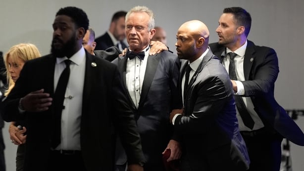 Law enforcement officers surround Robert F. Kennedy Jr, US secretary of Health and Human Services, following reports of a shooting during the White House Correspondents' Association Dinner.