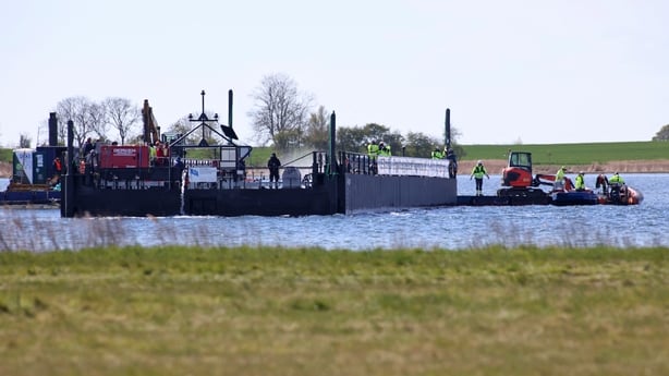 Members of a rescue team are seen on a special barge intended to bring a stranded humpback whale to the North Sea