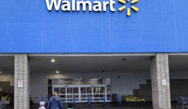 An adult and two children walk toward a Walmart entrance.