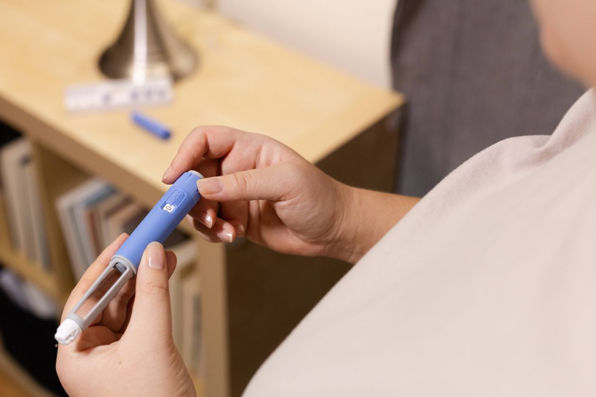 A young woman primes pre-filled pen injector with semaglutide