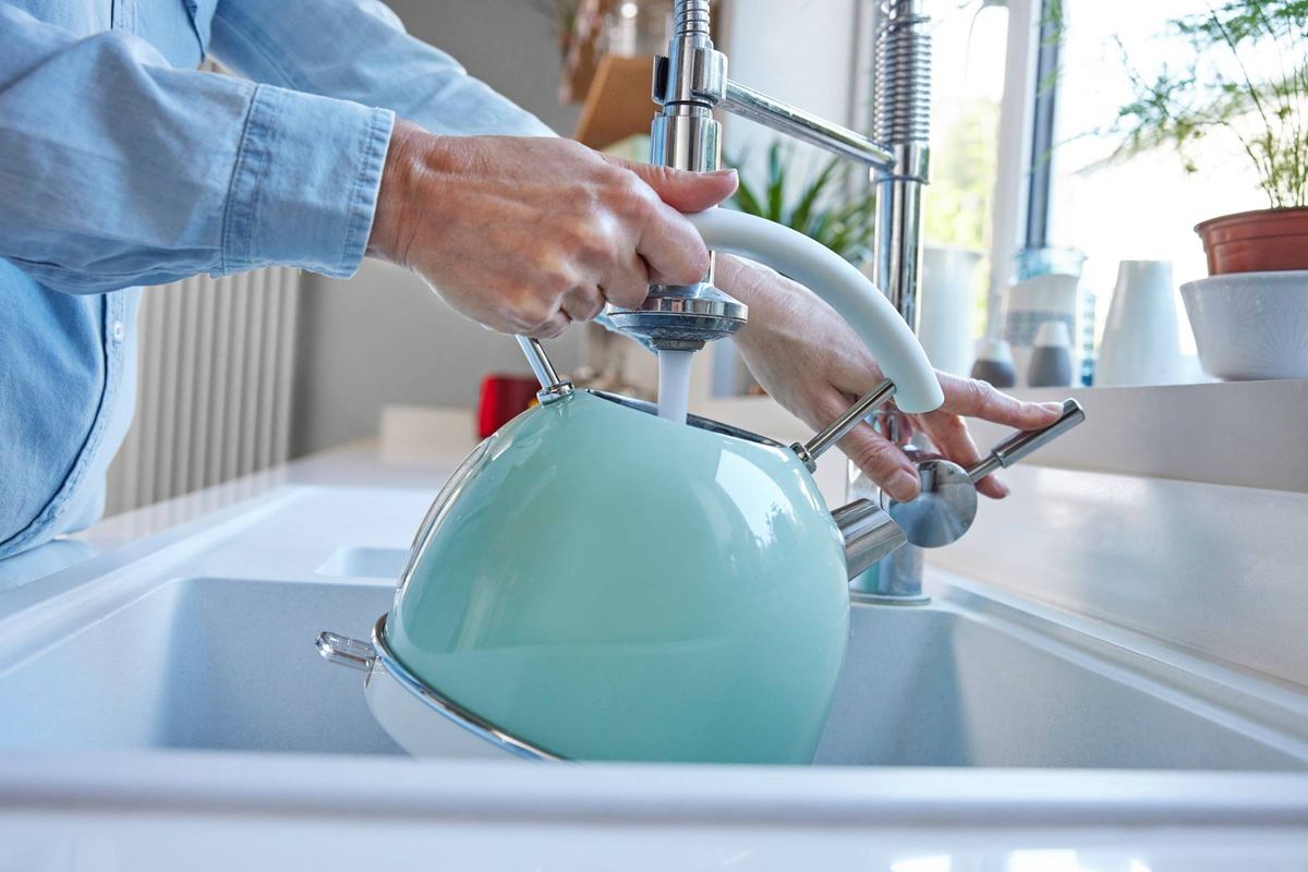 Close Up Of Woman Carefully Filling Kettle From Tap And Saving Water