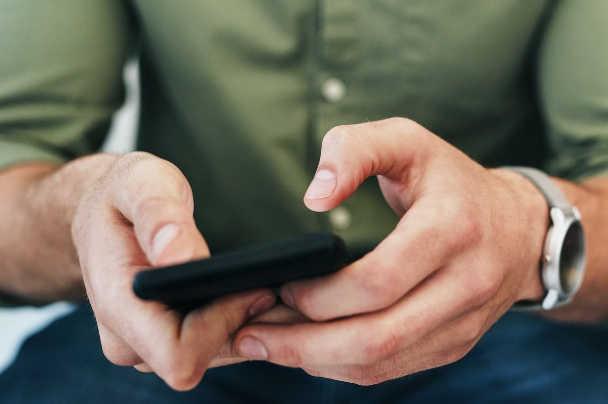 Cropped shot of an unrecongnizable businessman sitting alone in the office and texting on her cellphone