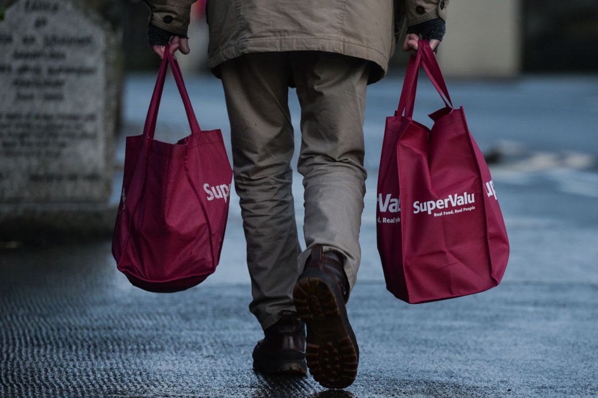 A man carries two SuperValu shopping bags in Dun Laoghaire - stock photo