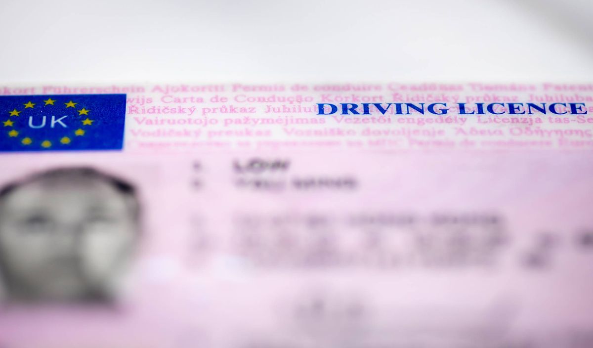 A close-up view of a pink driving license card featuring the European Union flag and the text "DRIVING LICENSE" printed in blue. The card includes additional details such as the holder's name and a barcode for identification purposes.