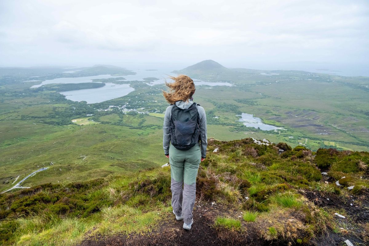 Woman standing at Connemara National Park viewpoint. Only the back of her is visible. Connemara National Park is one of eight national parks in Ireland