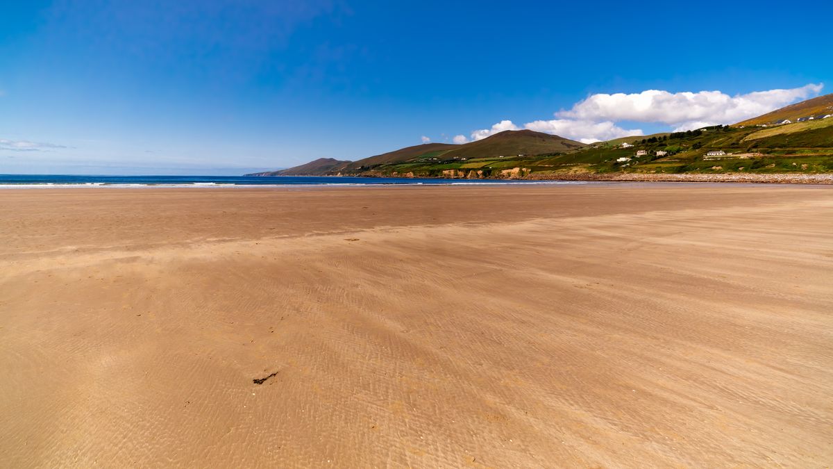 Long, beautiful sandy Inch Beach with mountains in seen in the background on a sunny day