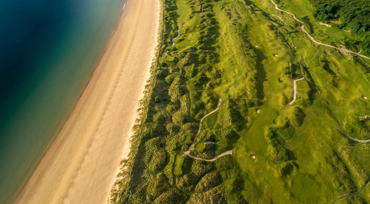 A bird's eye view of a beach and green coast in Portsalon in Ireland
