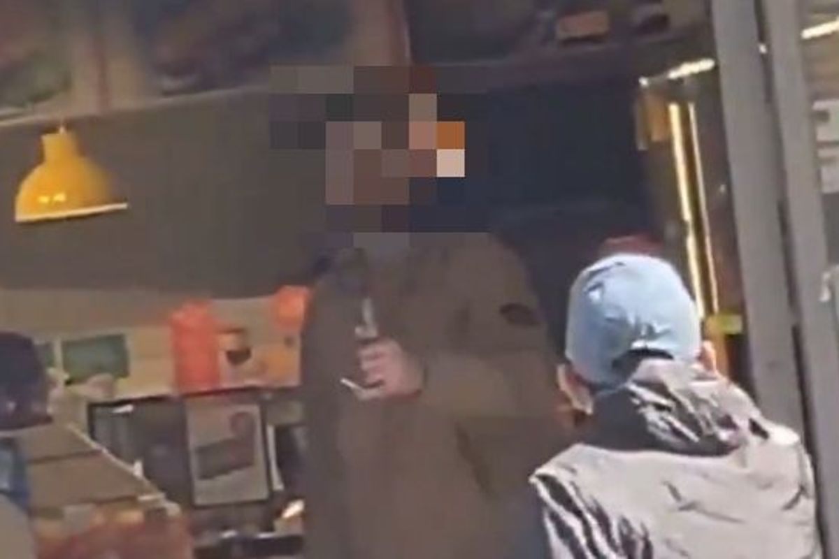 A man stands inside a Centra shop in Dublin brandishing what appears to be a knife. 