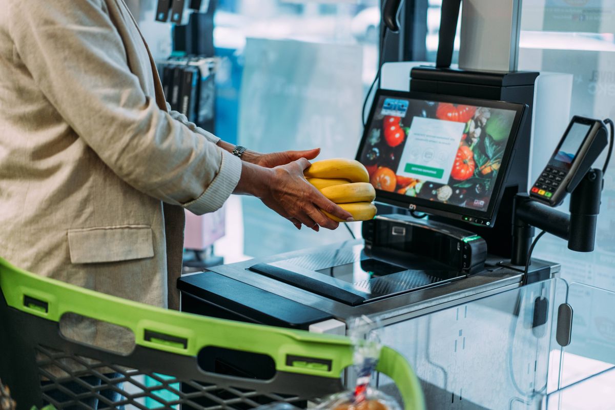 Shot of a woman scans products at the self-service checkout in the grocery supermarket shop. Woman buyer in a supermarket pays for goods at a self-service checkout.