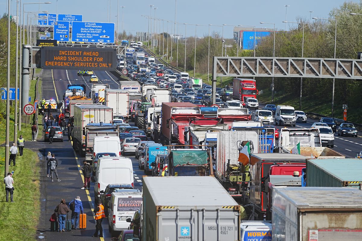 People with their luggage walk past the heavy traffic on Dublin's M50 Northbound, due to vehicles taking part on the third day of a National Fuel Protest against rising fuel prices. 