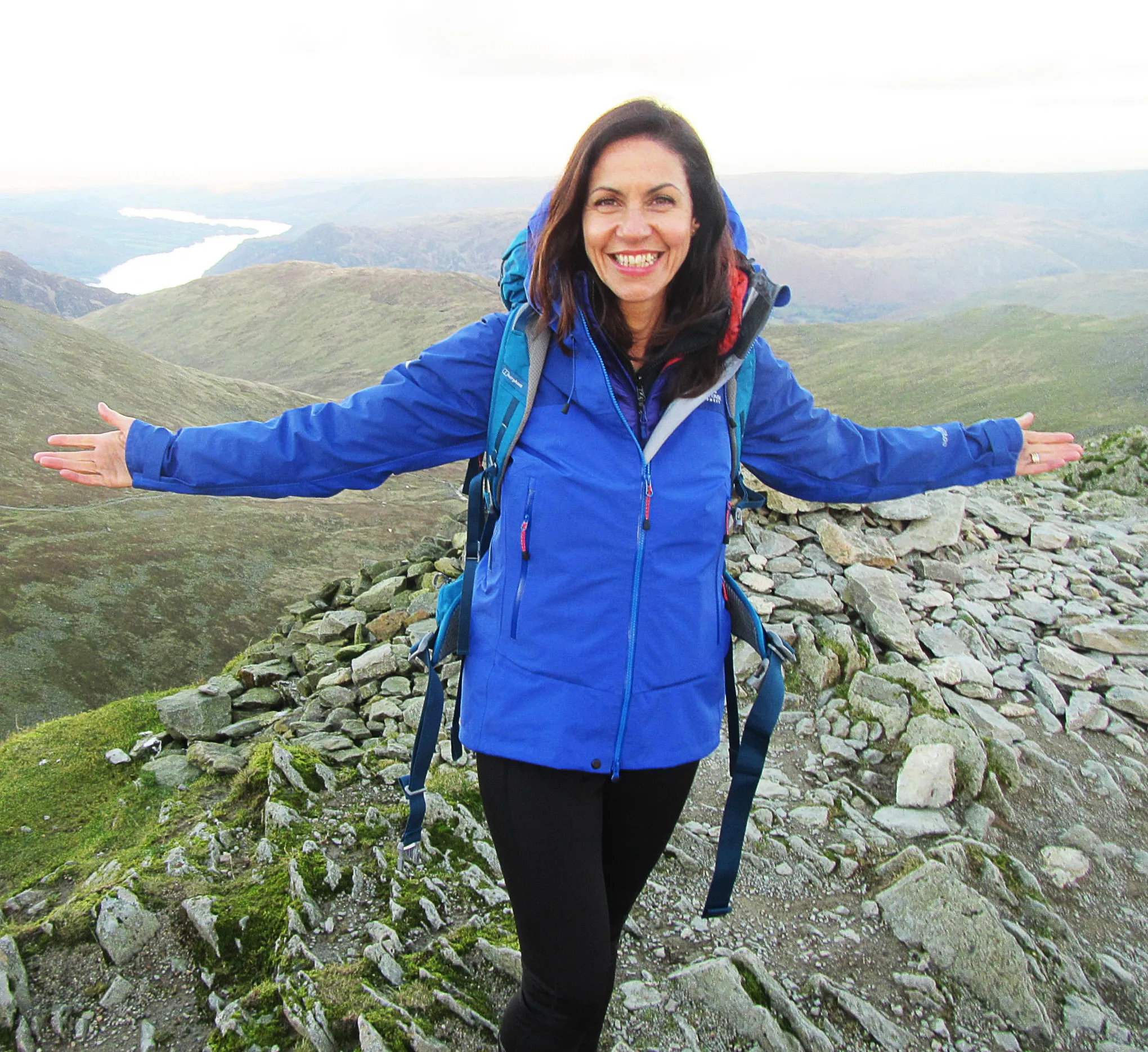 Julia Bradbury stands with arms outstretched on Helvellyn in the Lake District for "Britain's Favourite Walks: Top 100".