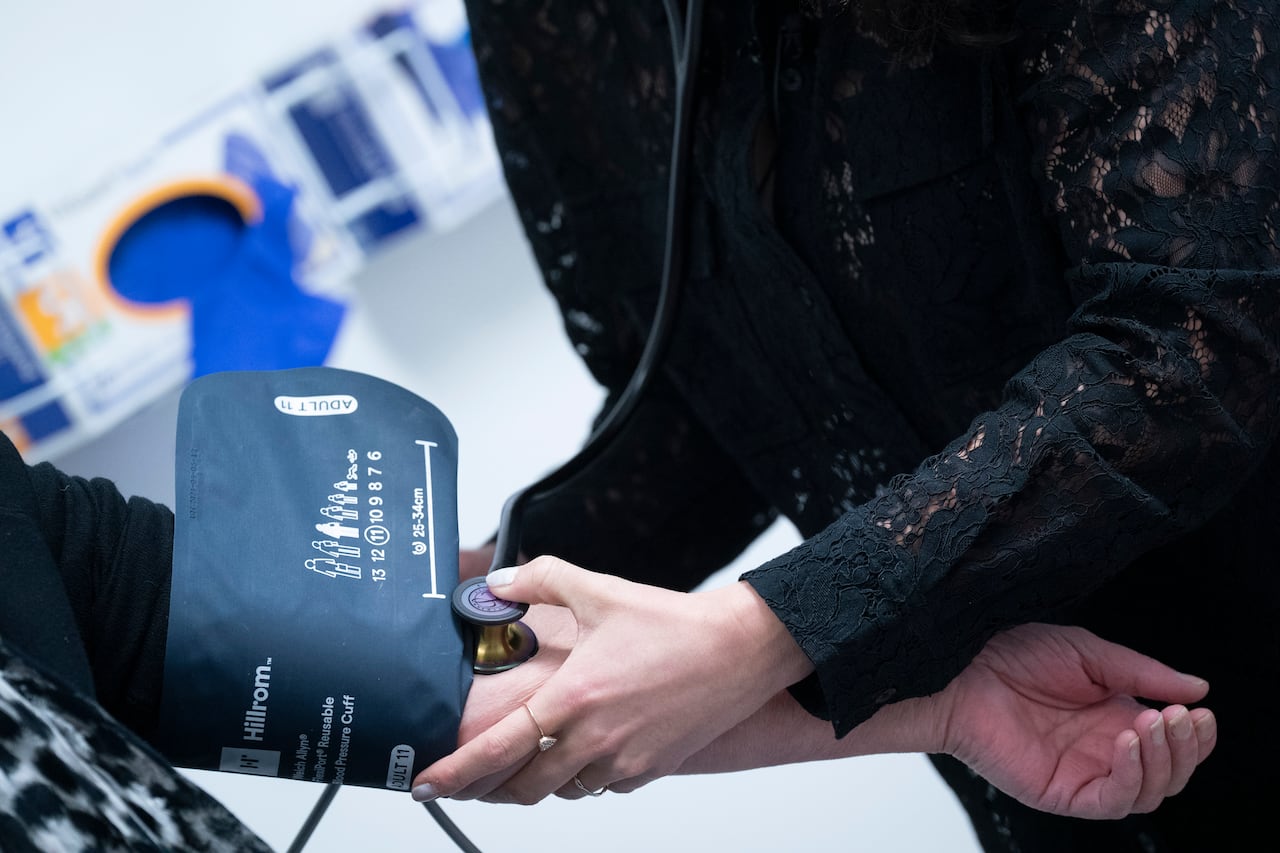 A clinician takes someone's blood pressure.