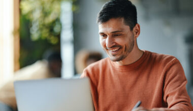 Male employee smiling while reading his laptop.