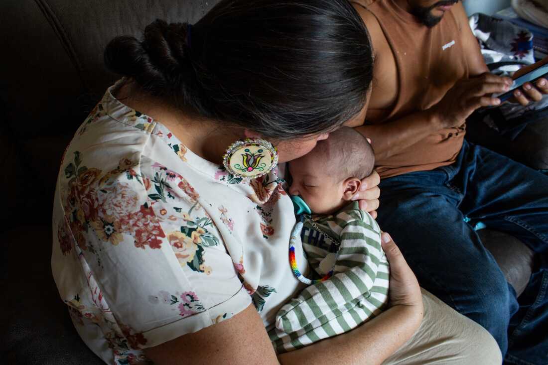 Doula Misty Pipe kisses the top of Grover’s head as his father, Torey WolfVoice, scrolls through photos of the baby boy’s namesake grandfather.