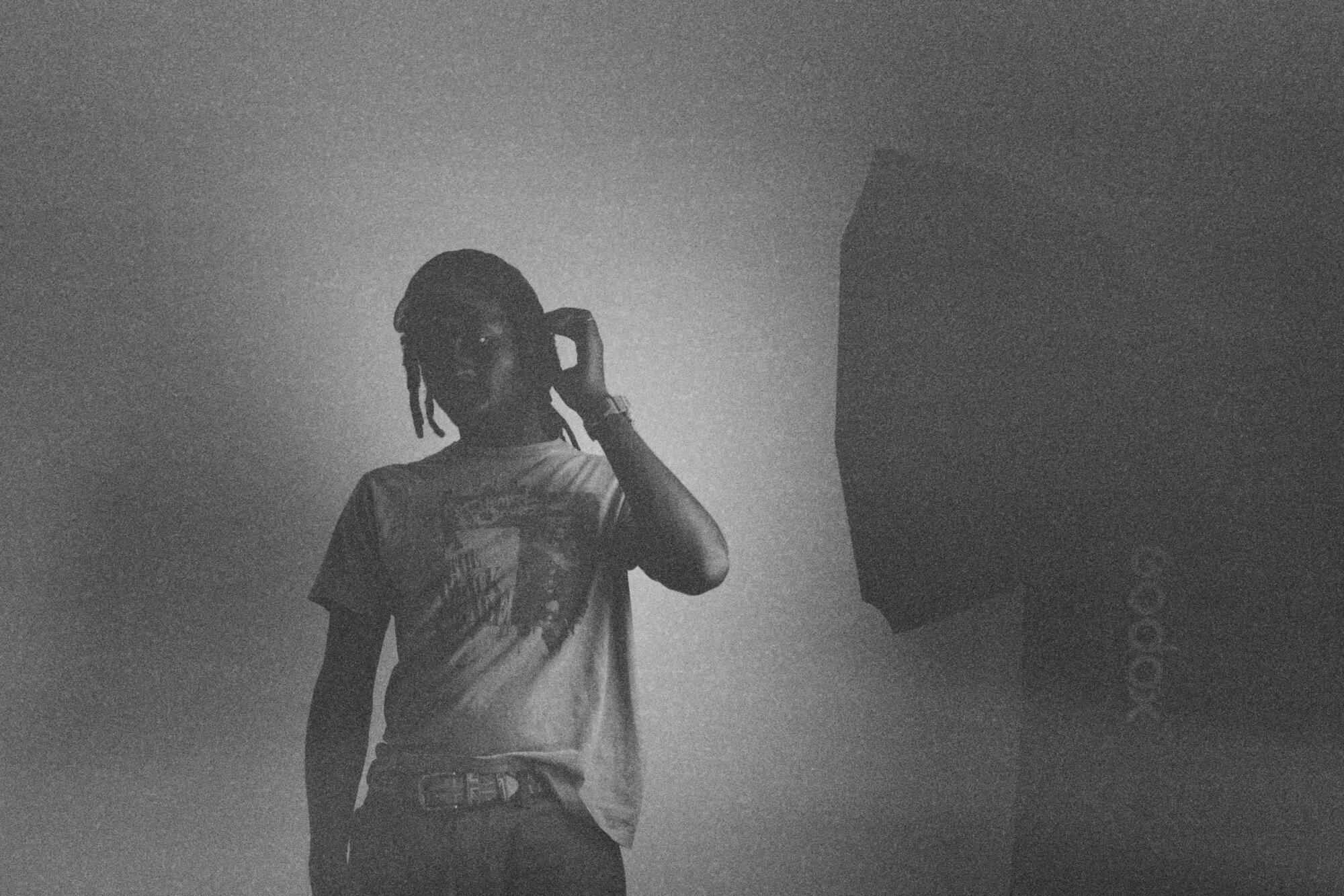 Devonte Hynes, known as Blood Orange, stands while wearing a white t-shirt and slim jeans.