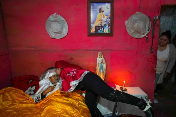 A pilgrim kisses her sick grandfather, Ramon Gamboa, after a priest blessed him at his home during the Quasimodo Feast, a procession held the Sunday following Easter, Colina, Chile, Sunday, April 12, 2026. (AP Photo/Esteban Felix)
