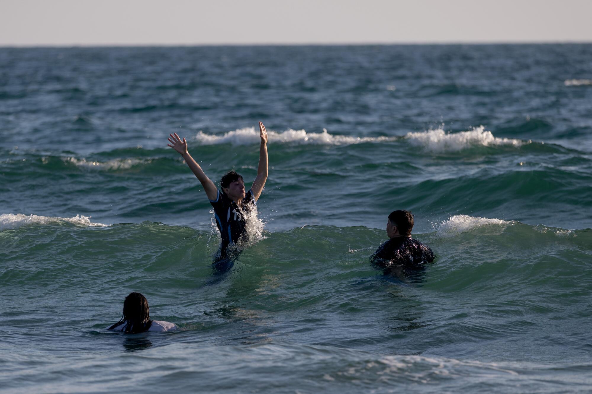Beachgoers play in the water near the Hermosa Beach Pier.