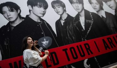 A fan of BTS poses in front of a poster at Tokyo Dome before the start of the K-pop band