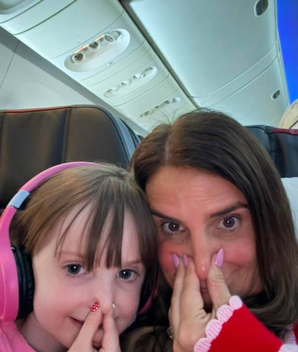 Sue and her daughter Heidi hold their noses on the plane