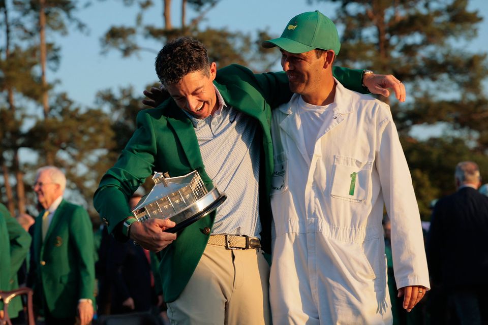 Golf - The Masters - Augusta National Golf Club, Augusta, Georgia, U.S. - April 12, 2026
Northern Ireland's Rory McIlroy with his caddie Harry Diamond as he celebrates with his green jacket and the trophy after winning The Masters REUTERS/Brian Snyder