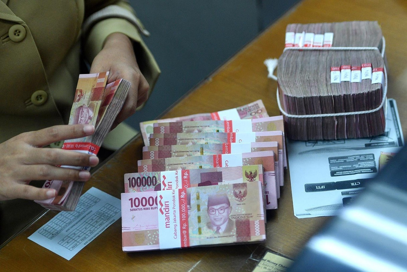 An employee counts rupiah bills on March 14 at a money changer in Jakarta.