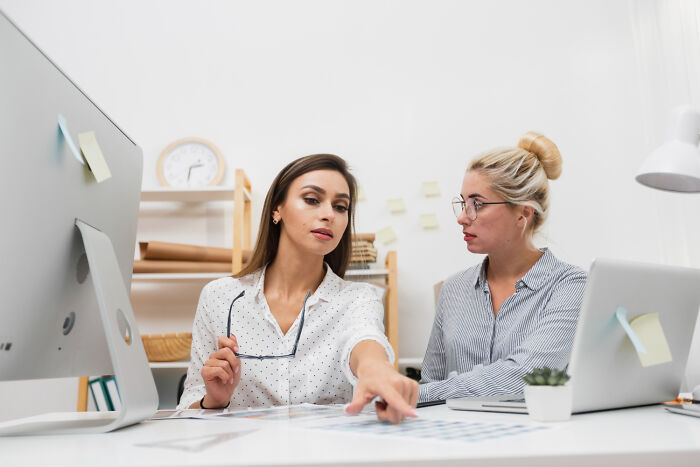 Two women discussing documents at a desk, highlighting hidden truths that may scare those who dislike hospitals.