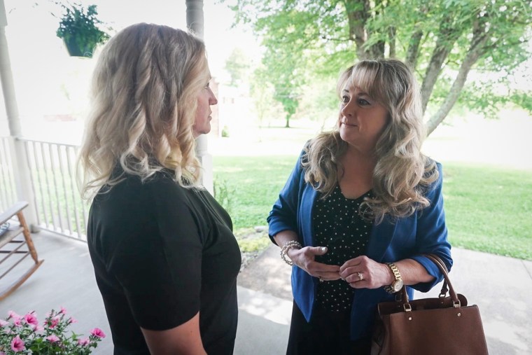 Becky Tennant, left, and Laura Kimble speak outside on the front porch of a house