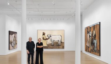 Two people standing in an art gallery with large paintings depicting figures and a cow on the white walls.