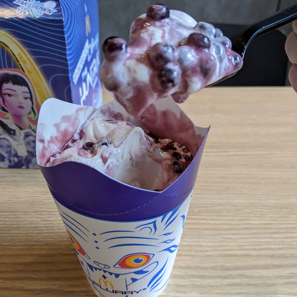 Cup of dessert with purple and white swirls, topped with berries.