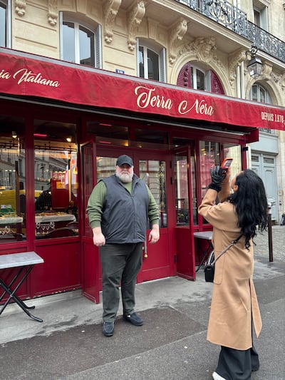 Valerio Abate, owner of a restaurant made famous by its appearance in the series Emily in Paris, stands outside as a tourist takes a photograph. Photograph: Naomi O'Leary