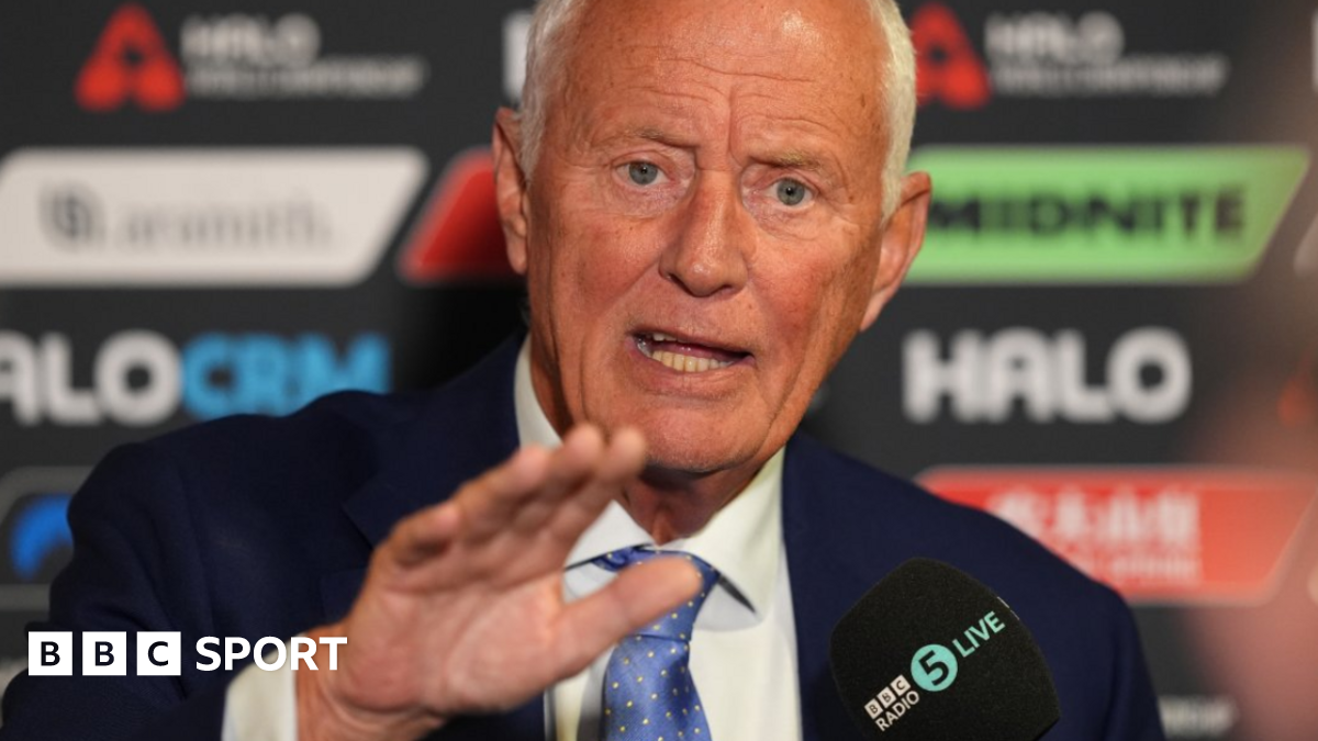 Barry Hearn holds his right hand out in front of him as he talks in a media conference, wearing a mostly light blue tie, white shirt and blue smart jacket