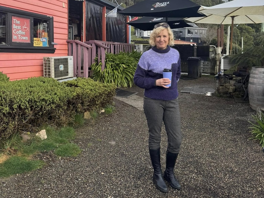 A woman stands outside a shop building.