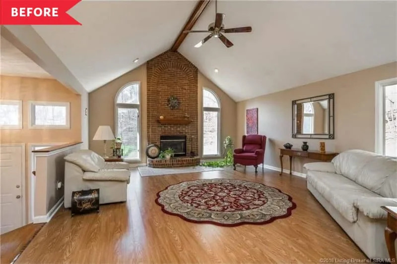 Before: Large living room with tall brick fireplace and honey oak floors
