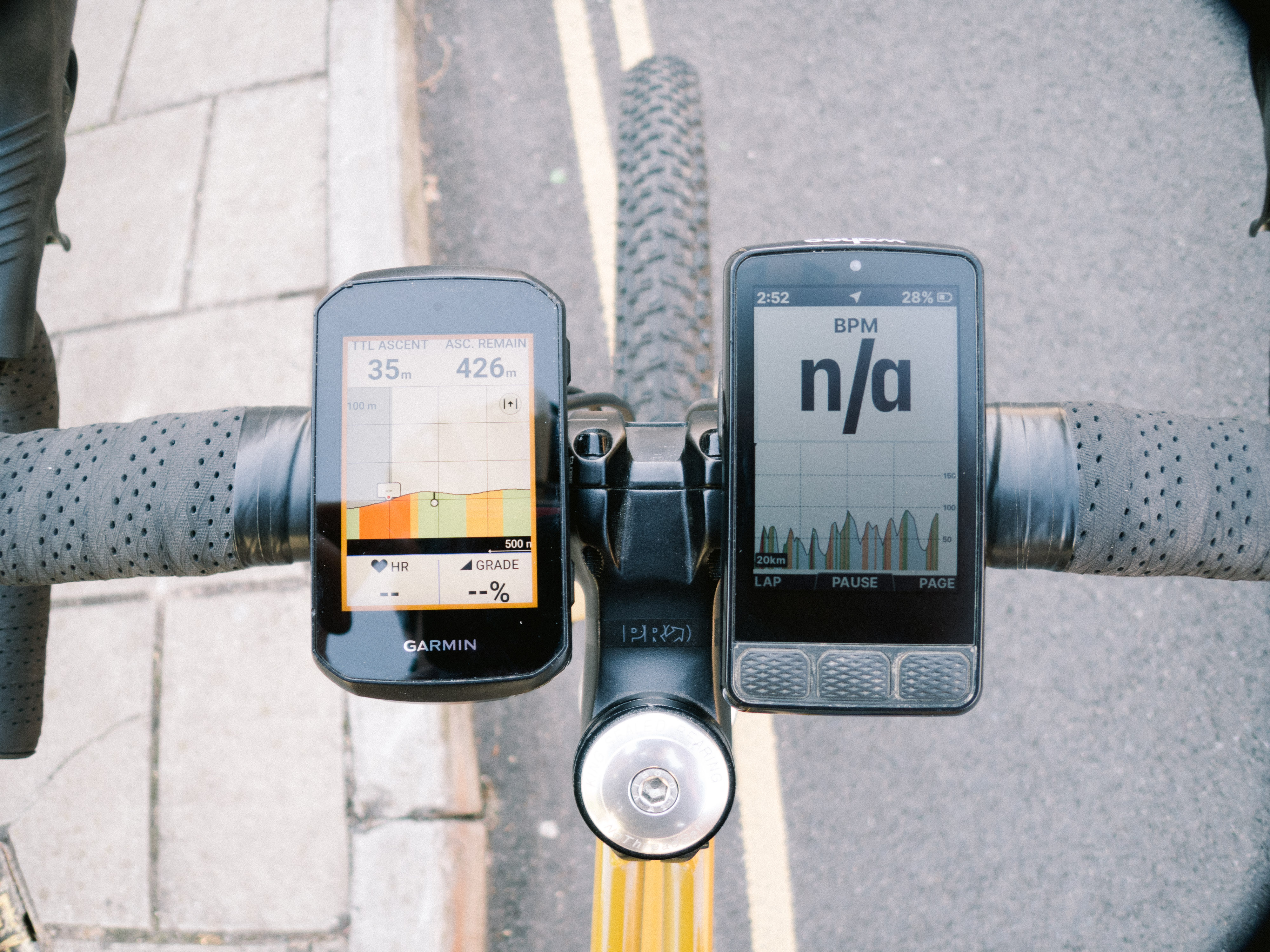 Two bike computers side by side on a gravel bike handlebar