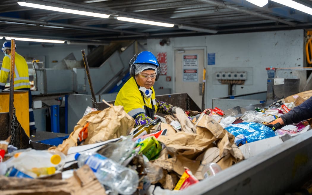 Staff work at the PreSort at Auckland's Material Recovery Facility in Onehunga, where things that shouldn’t be in recycling are pulled out by hand. It’s on two conveyor belts and moving fast.