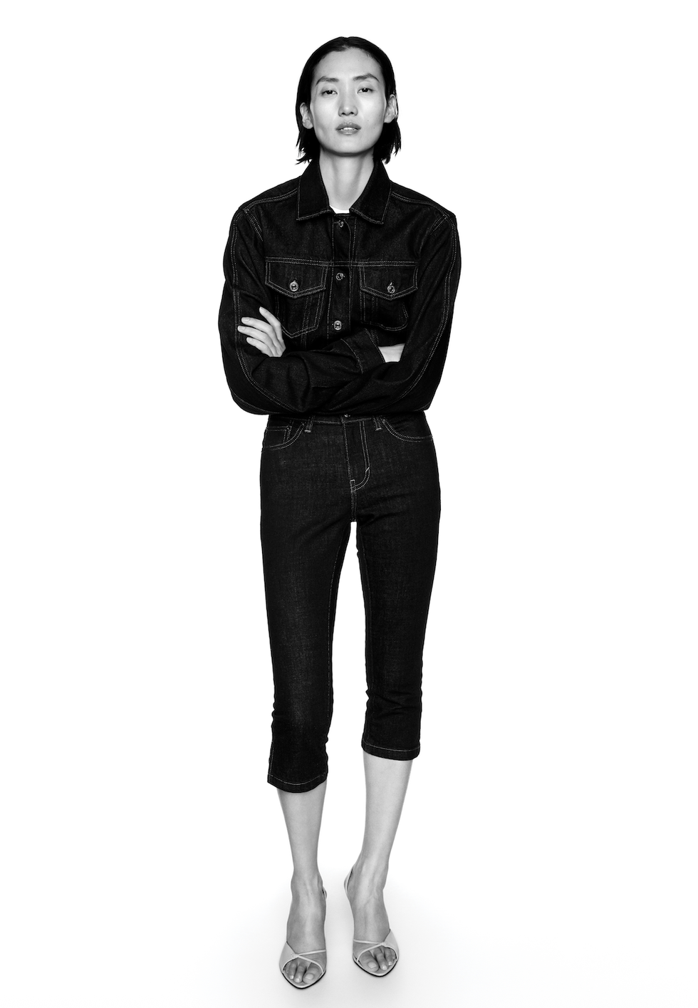 Model wearing black denim outfit with arms crossed