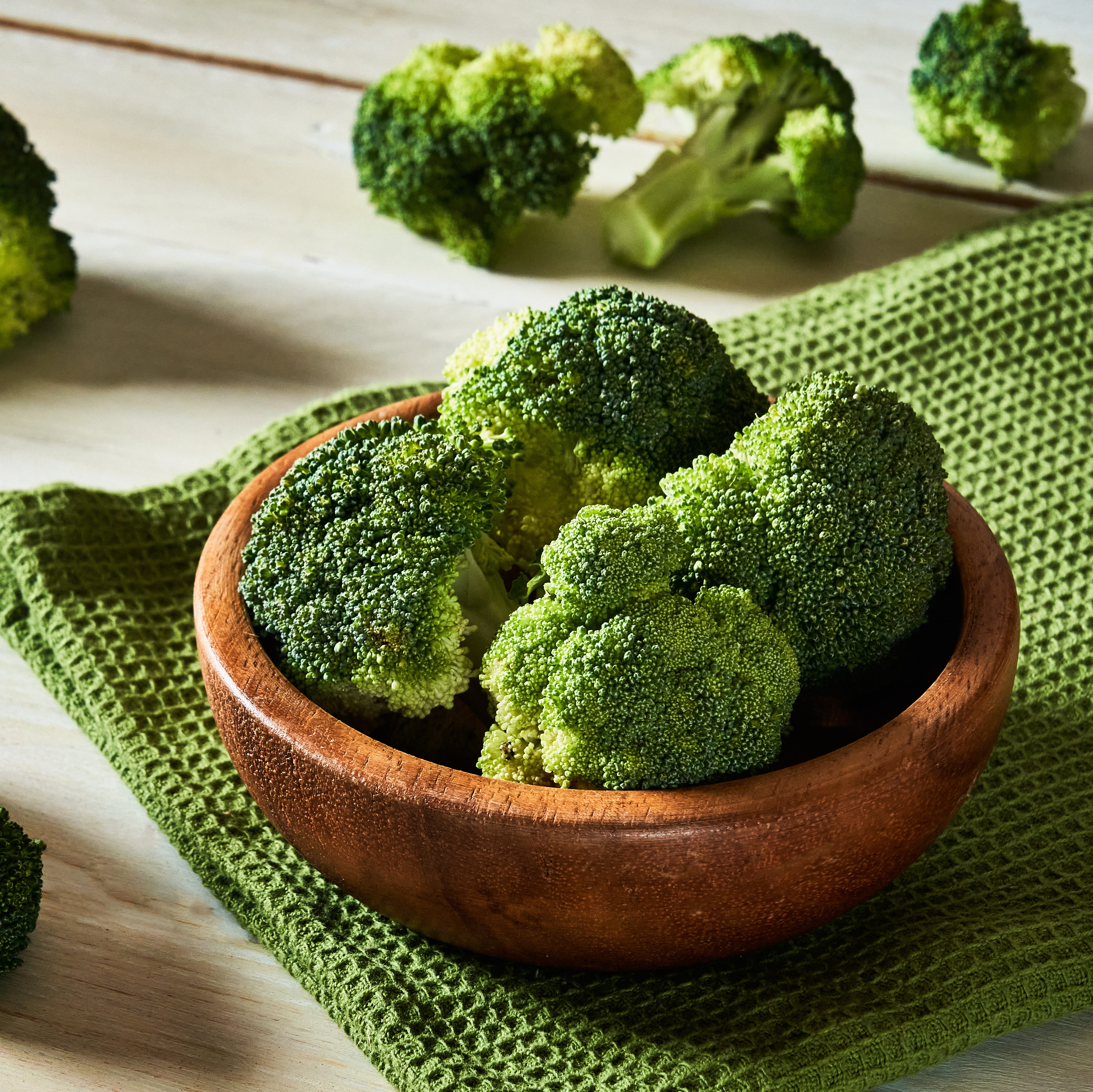Fresh raw broccoli in bowl on rustic table.