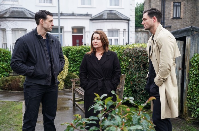 Mark, Vicki and Zack stand awkwardly in the Square Gardens in a scene from EastEnders