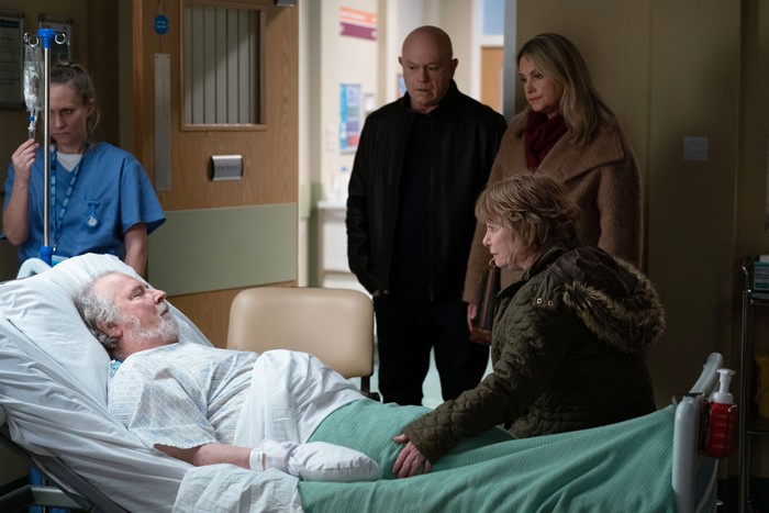 557174,TITLE:Eastenders Sam and Grant stand over Julie, who is sat on the bed beside Nigel in hospital in a scene from EastEnders