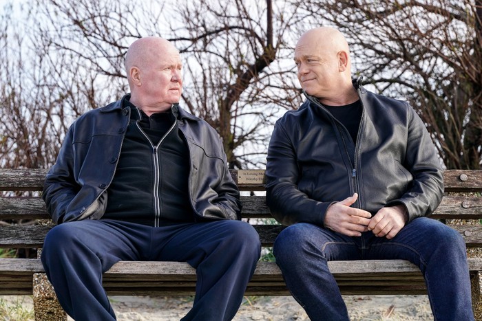 557932,TITLE:Eastenders Phil and Grant look at one another sat on a bench in a scene from EastEnders