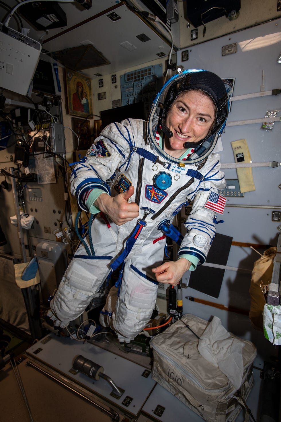 Astronaut floating in a spacecraft, giving a thumbs up.