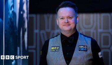 A smiling Shaun Murphy in black shirt and bow tie, and grey waistcoat