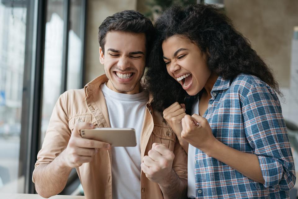 Two people excitedly look at a smartphone.