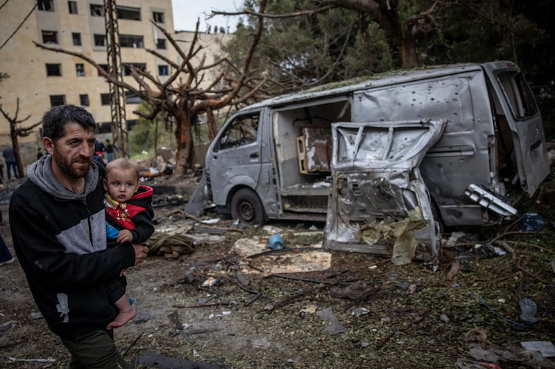 A man carries his child as he walks past destroyed vehicles and debris at the site of an overnight Israeli air strike that killed seven people in Beirut, Lebanon, on Wednesday. Photograph: Chris McGrath/Getty